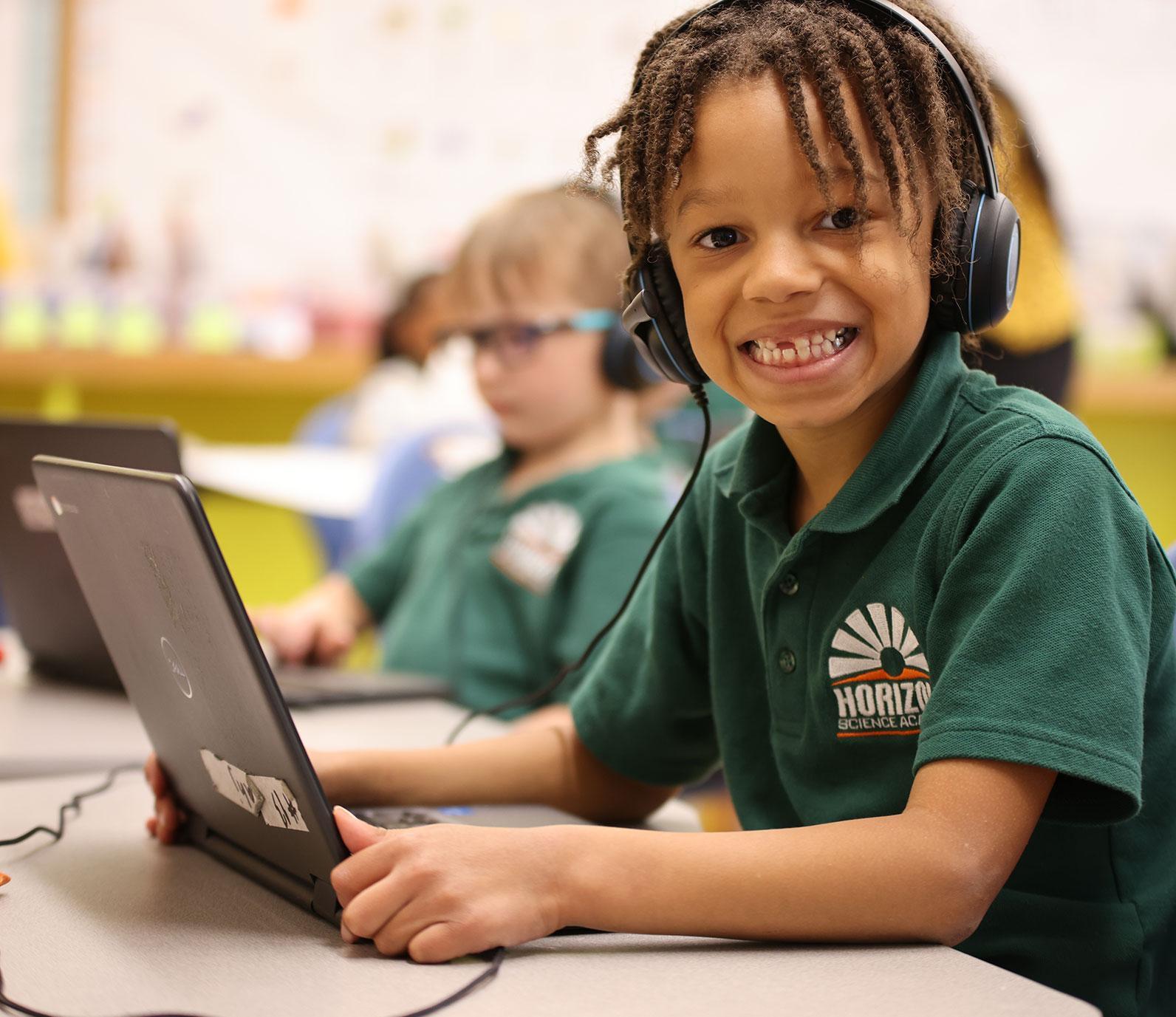 HSA Des Moines student wearing headphones uses a laptop in class