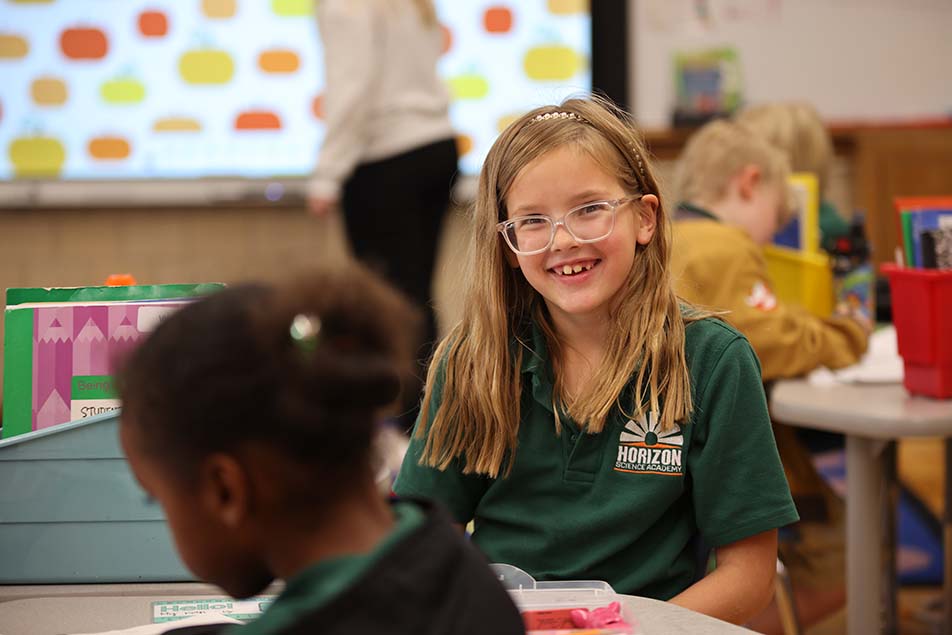 student in classroom smiling at camera